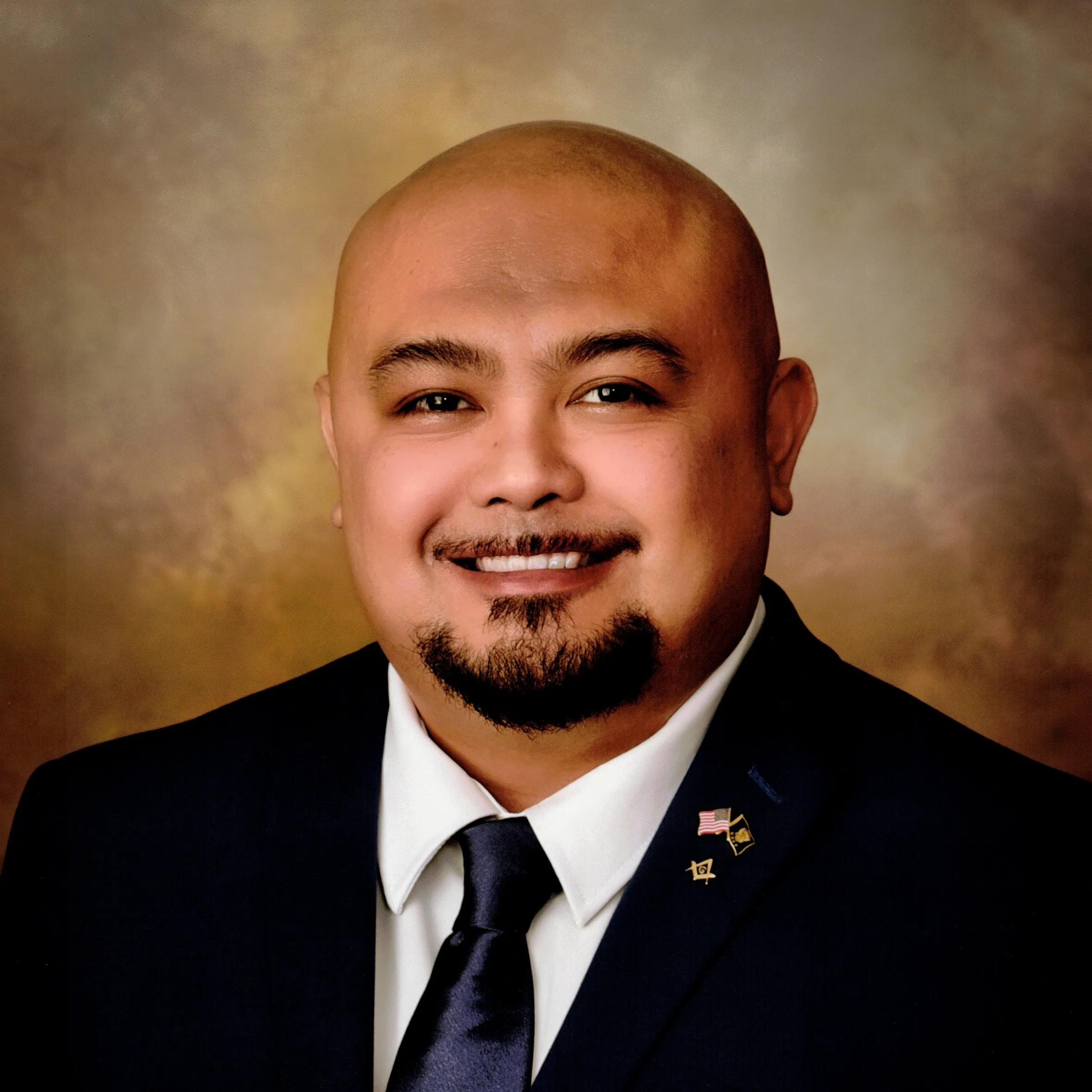 Jonathan Cruz smiling in a formal suit-and-tie headshot.
